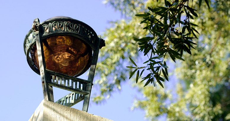Top of Maxcy Monument with blue sky and green branches in the background